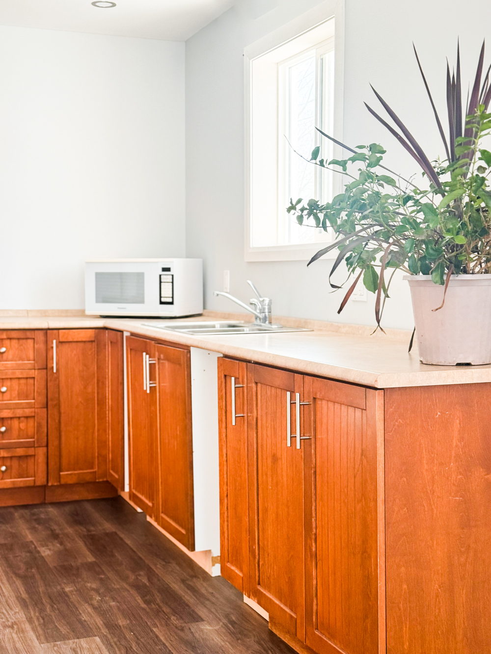 Cuisine partagée lumineuse avec table haute, tabourets et réfrigérateur, accessible pour les personnes qui louent une salle ou un bureau dans l’espace.